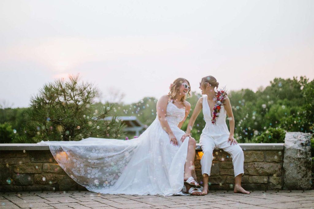 Brides laugh as they are surrounded by bubbles at the Green Bay Botanical Garden.