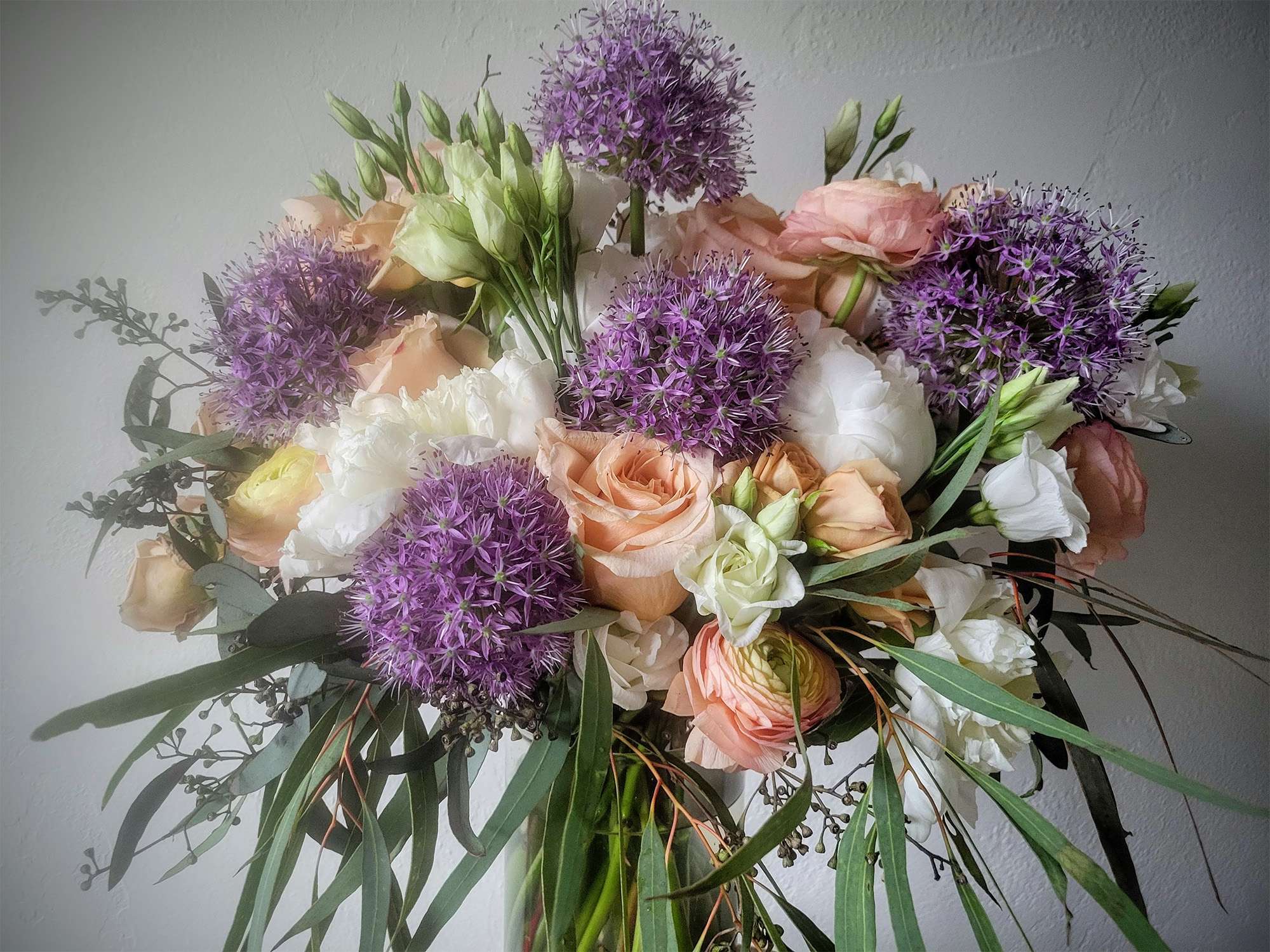 Lush bridal bouquet with peach, lavender and cream colored flowers.