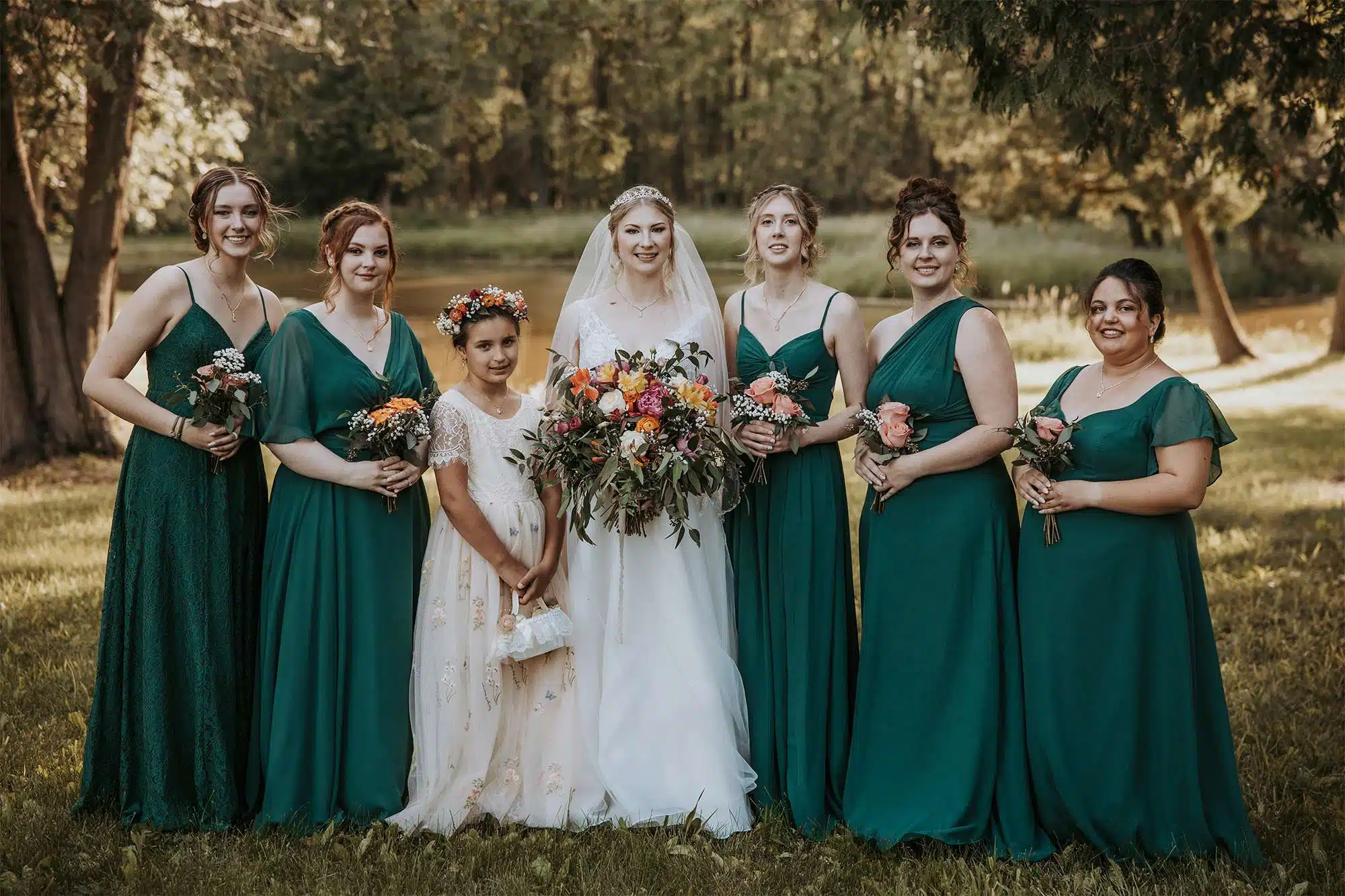 Bride with bridesmaids in green dresses holding bouquets by Archer & Bliss Floral, outdoor wedding party portrait