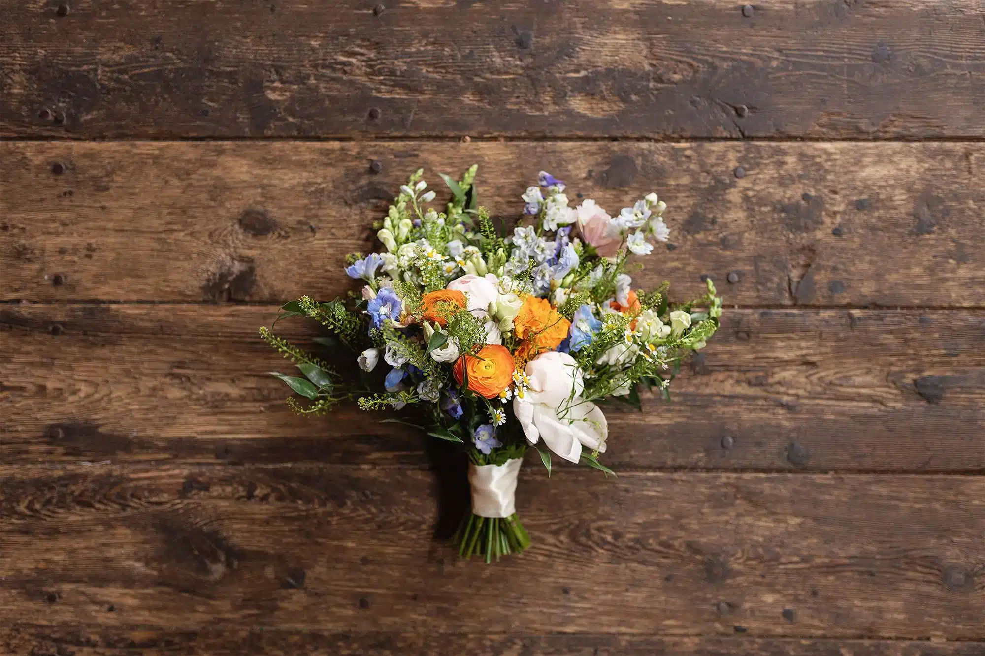 Vibrant floral bridal bouquet laid on wood floor.