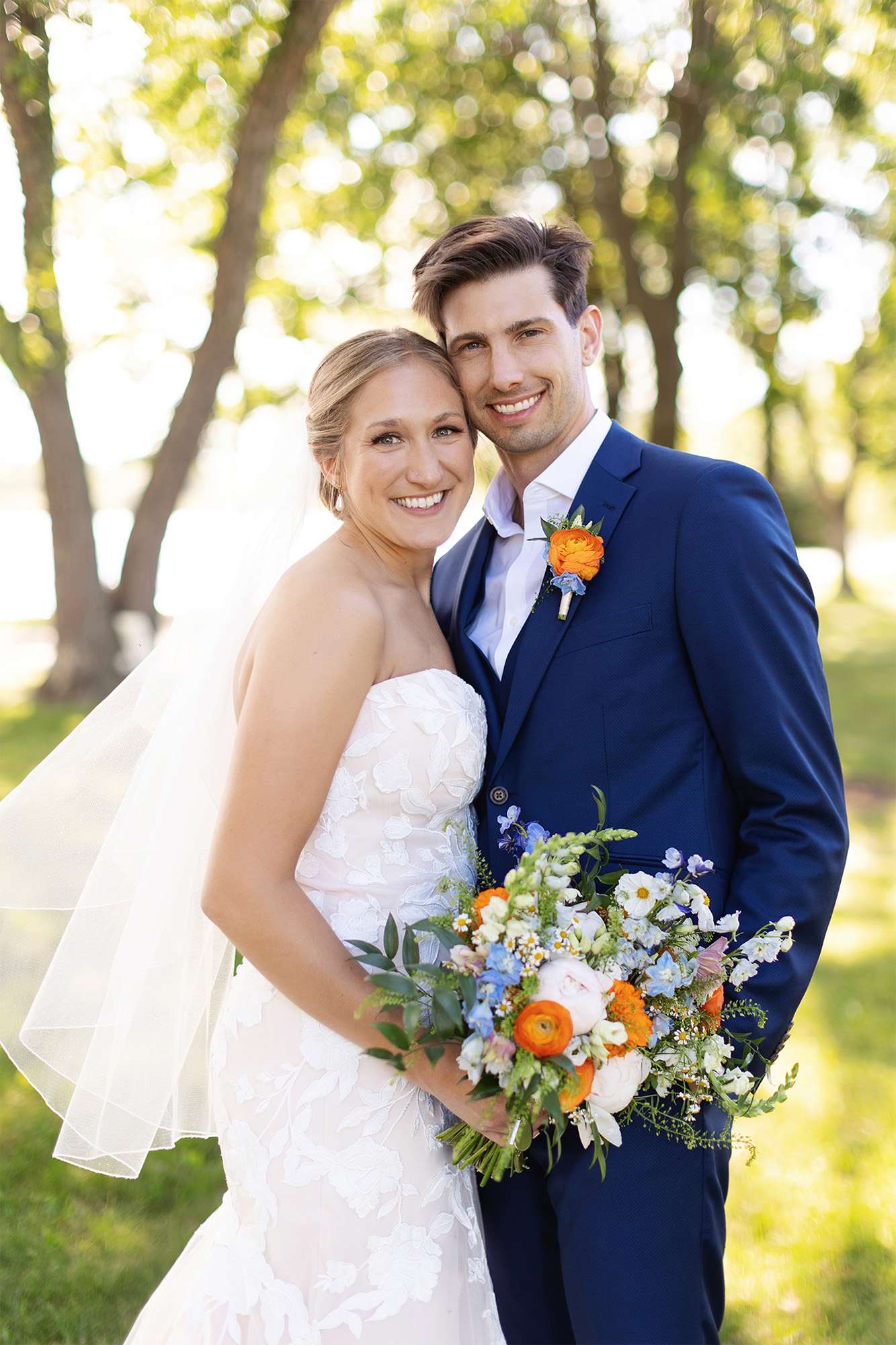 Summer bride and groom pose with her bright floral bouquet by Archer & Bliss Floral.