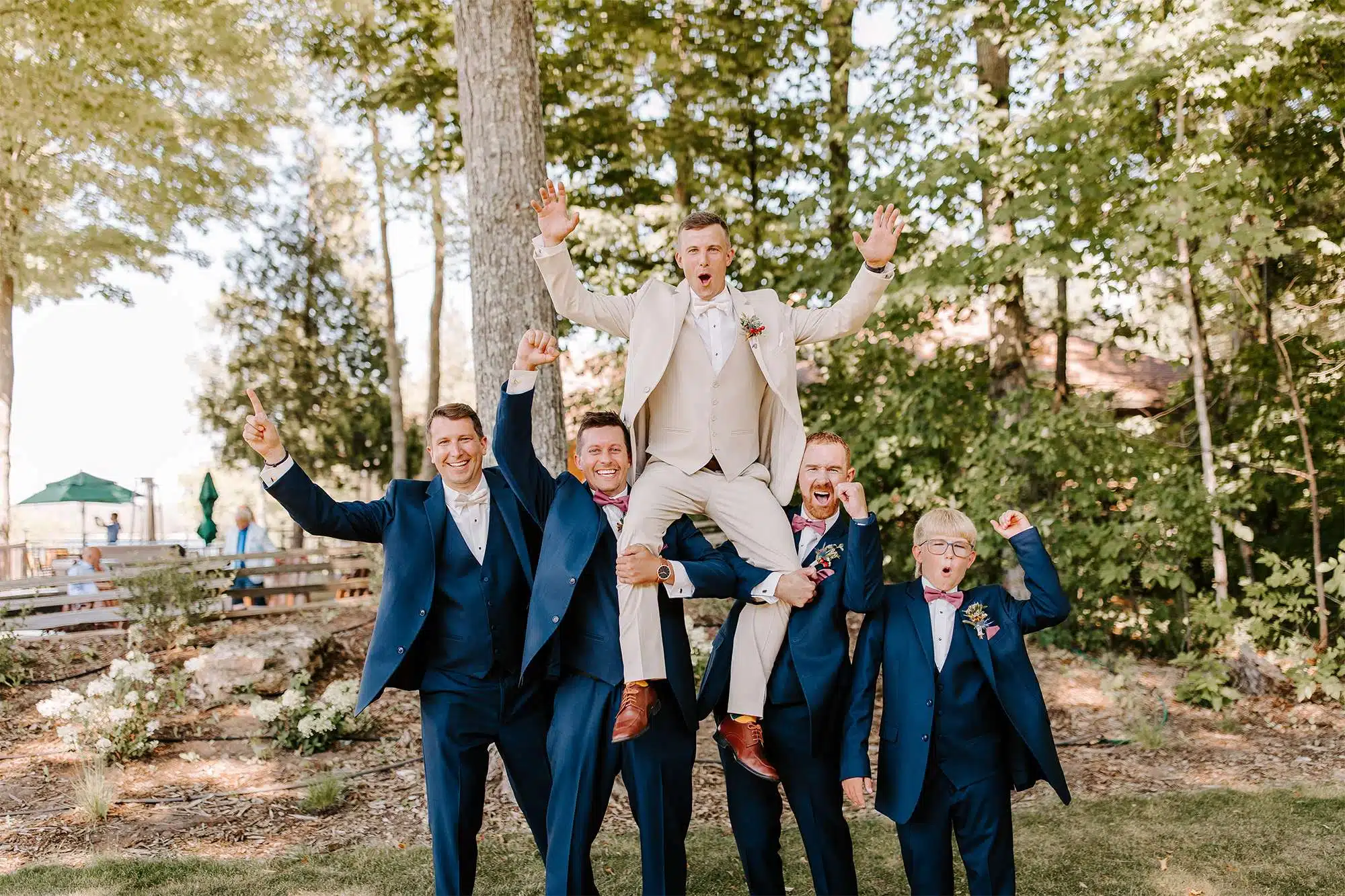 Groom is held up on groomsmen shoulders.