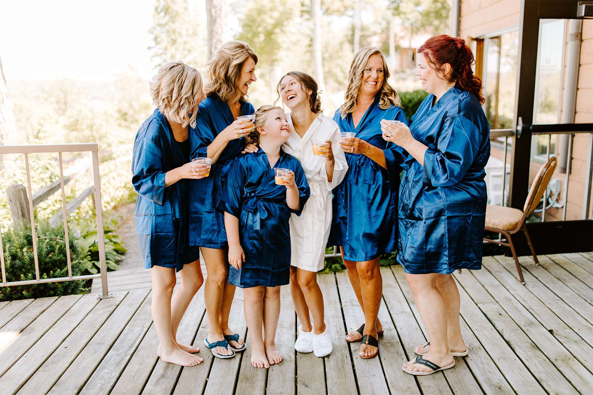 Bride and wedding party pose in silk robes on deck.