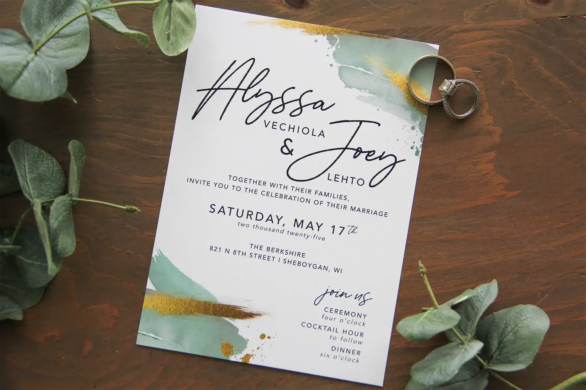 White wedding invitations with strokes and splatters of color in sage green and gold
