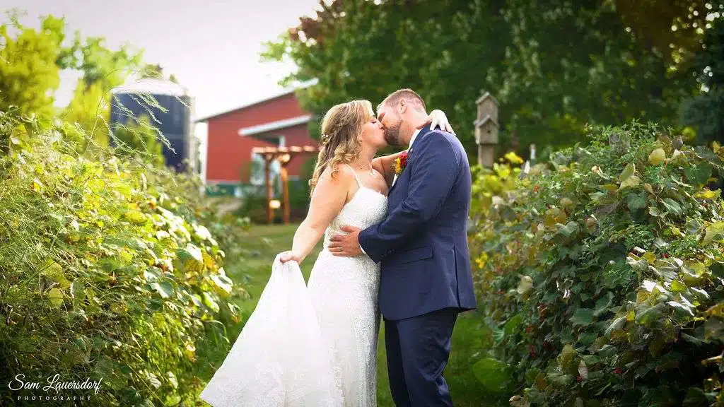 Newlyweds kiss near barn.
