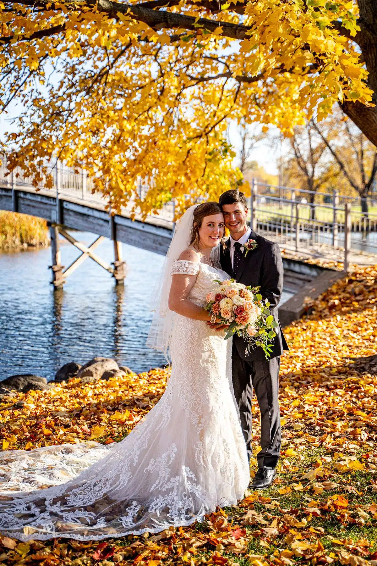 Bride and groom pose in fall park.