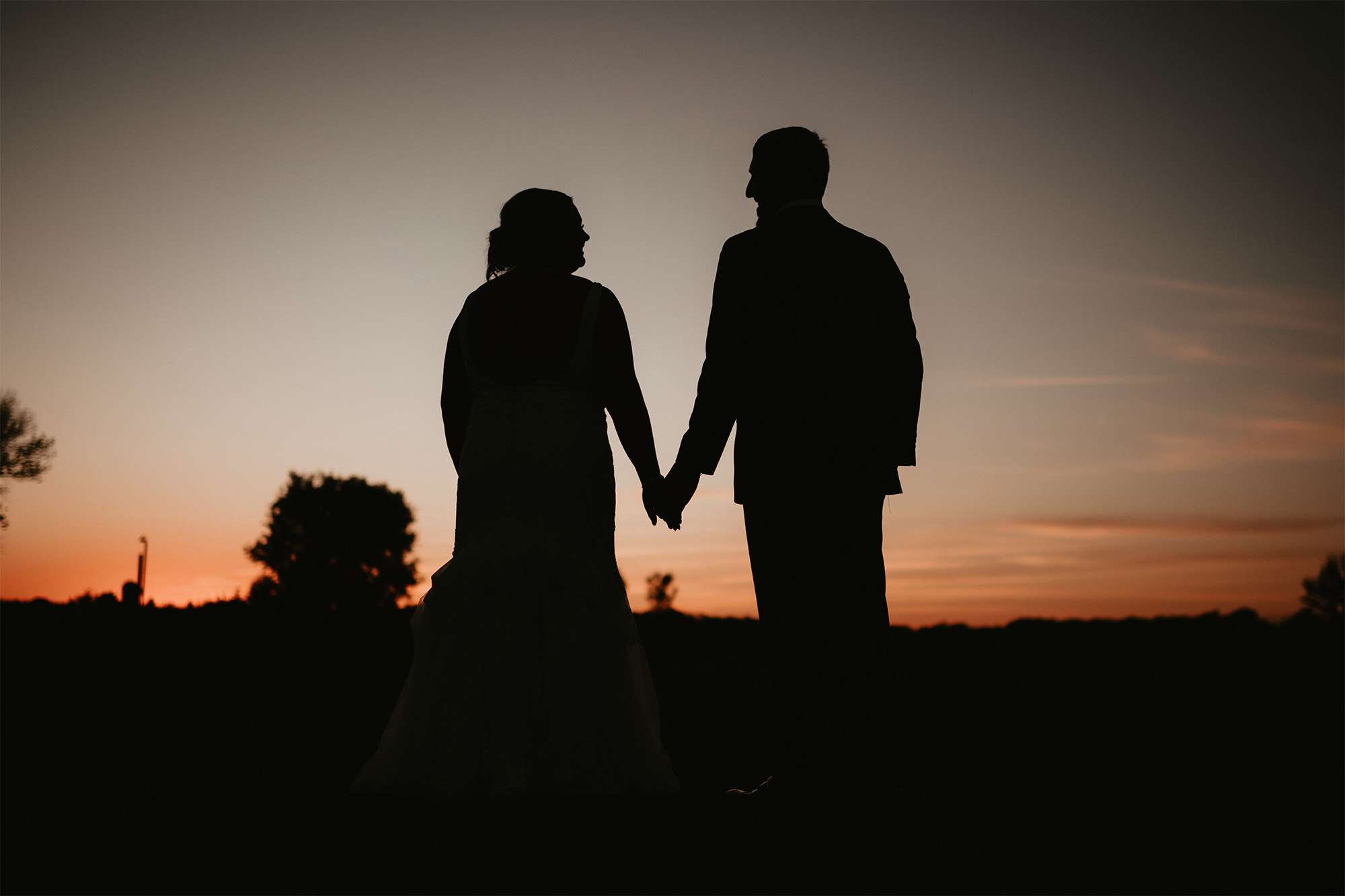 Bride and Groom holding hands at sunset at the Barn at Sunset Acres