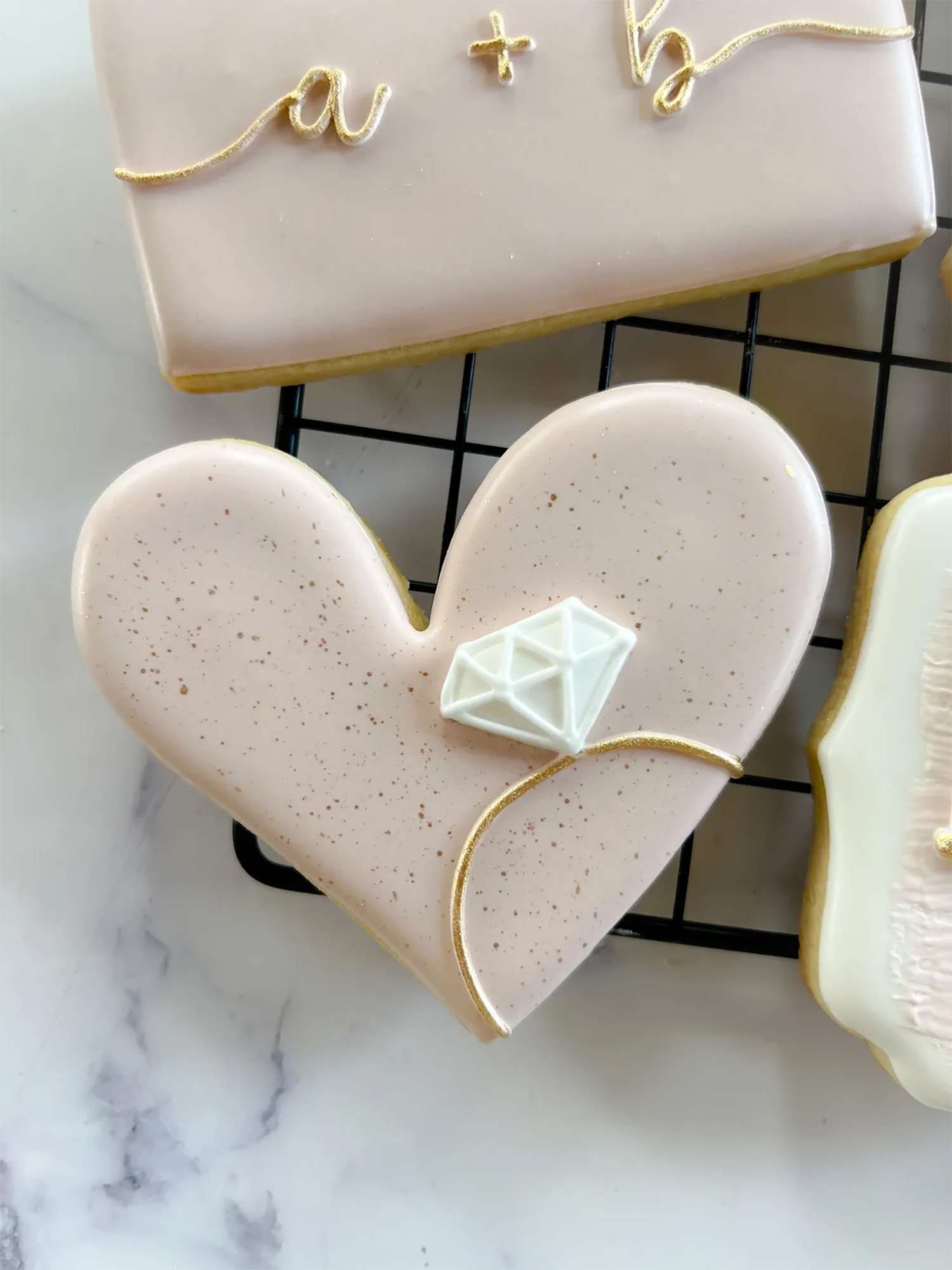 Heart shaped pale pink cookie with diamond ring design.