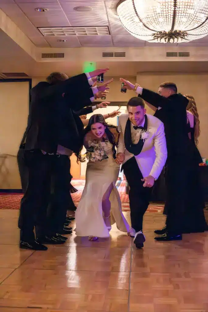 Bride and groom making a lively reception entrance under a tunnel of wedding party guests at Tundra Lodge Resort & Conference Center