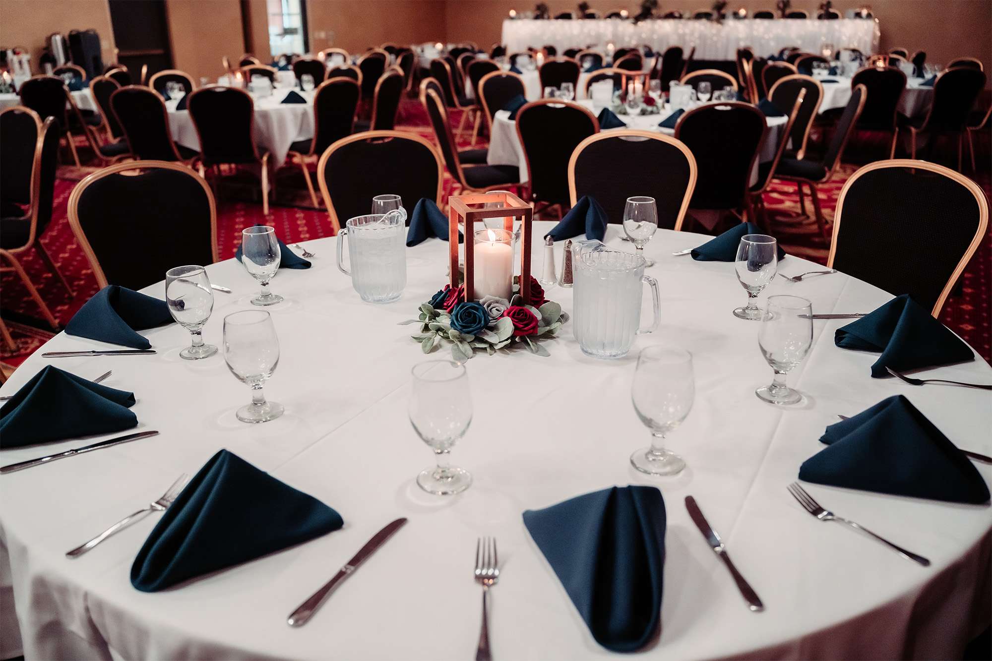 Wedding reception table with candle lantern centerpiece and navy napkins at Tundra Lodge Resort & Conference Center.