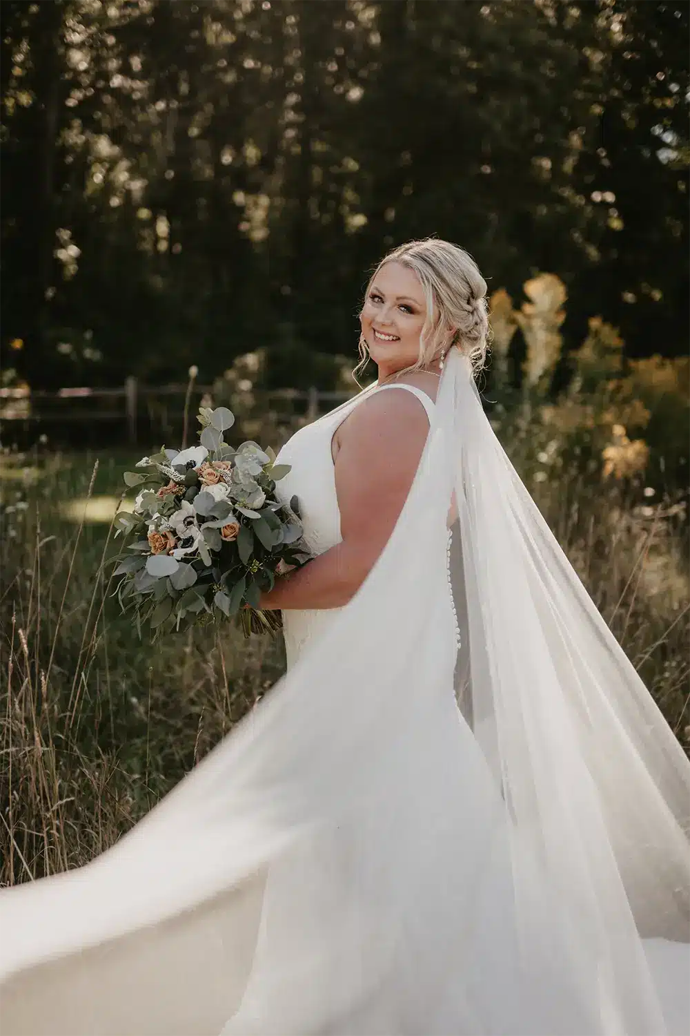 Beautiful bride in a Justin Alexander wedding gown poses in field. Beautiful bride in a Justin Alexander wedding gown poses in field.