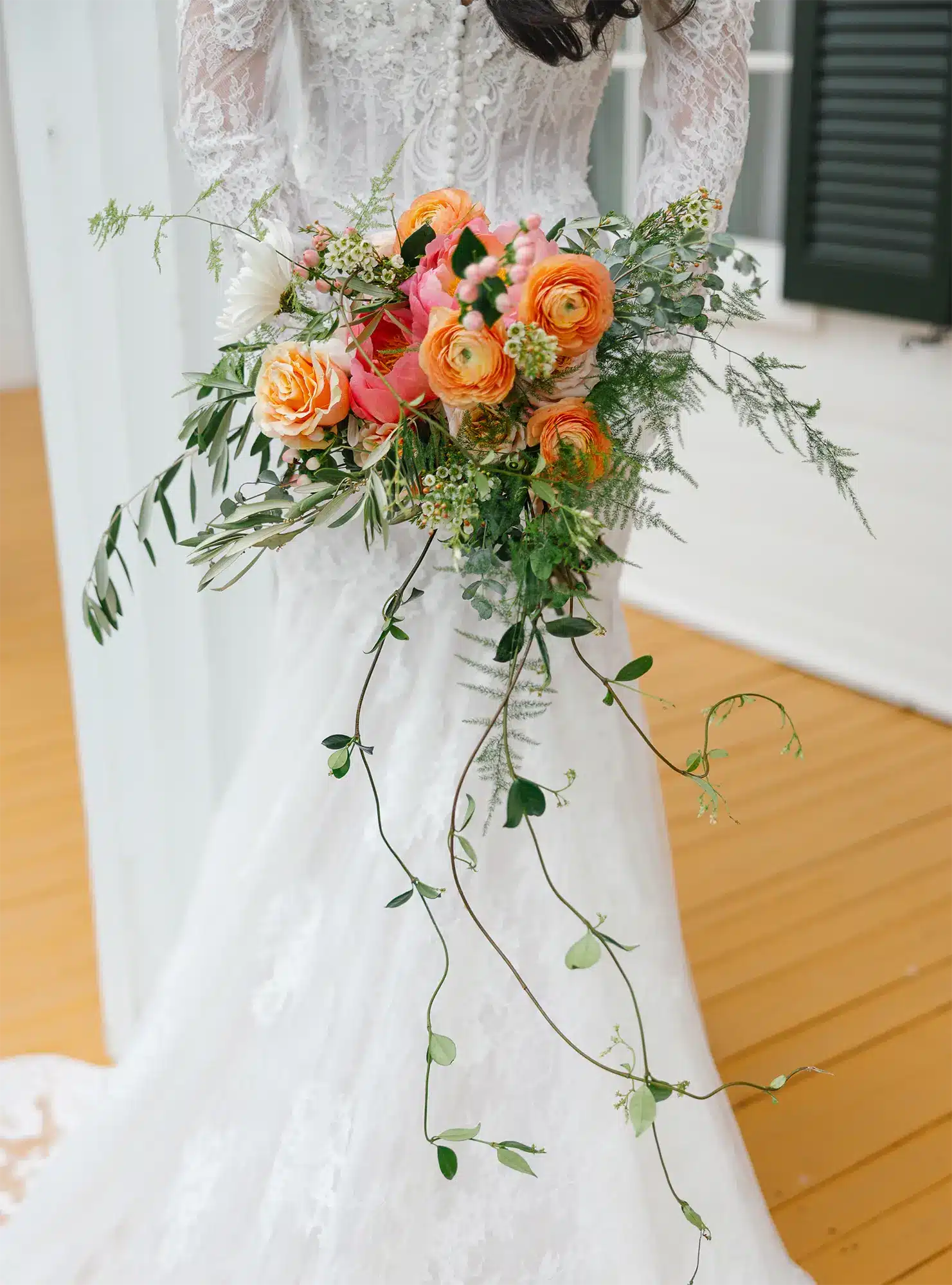 Bride holding vibrant orange bouquet.