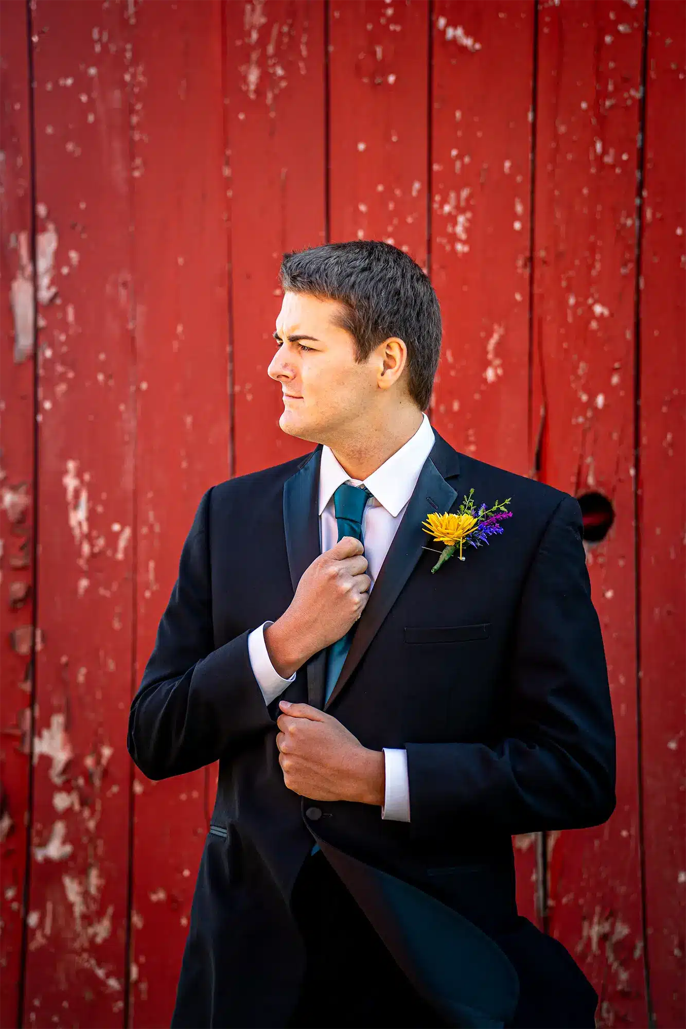 Groom poses by red weathered barn. Groom poses by red weathered barn.