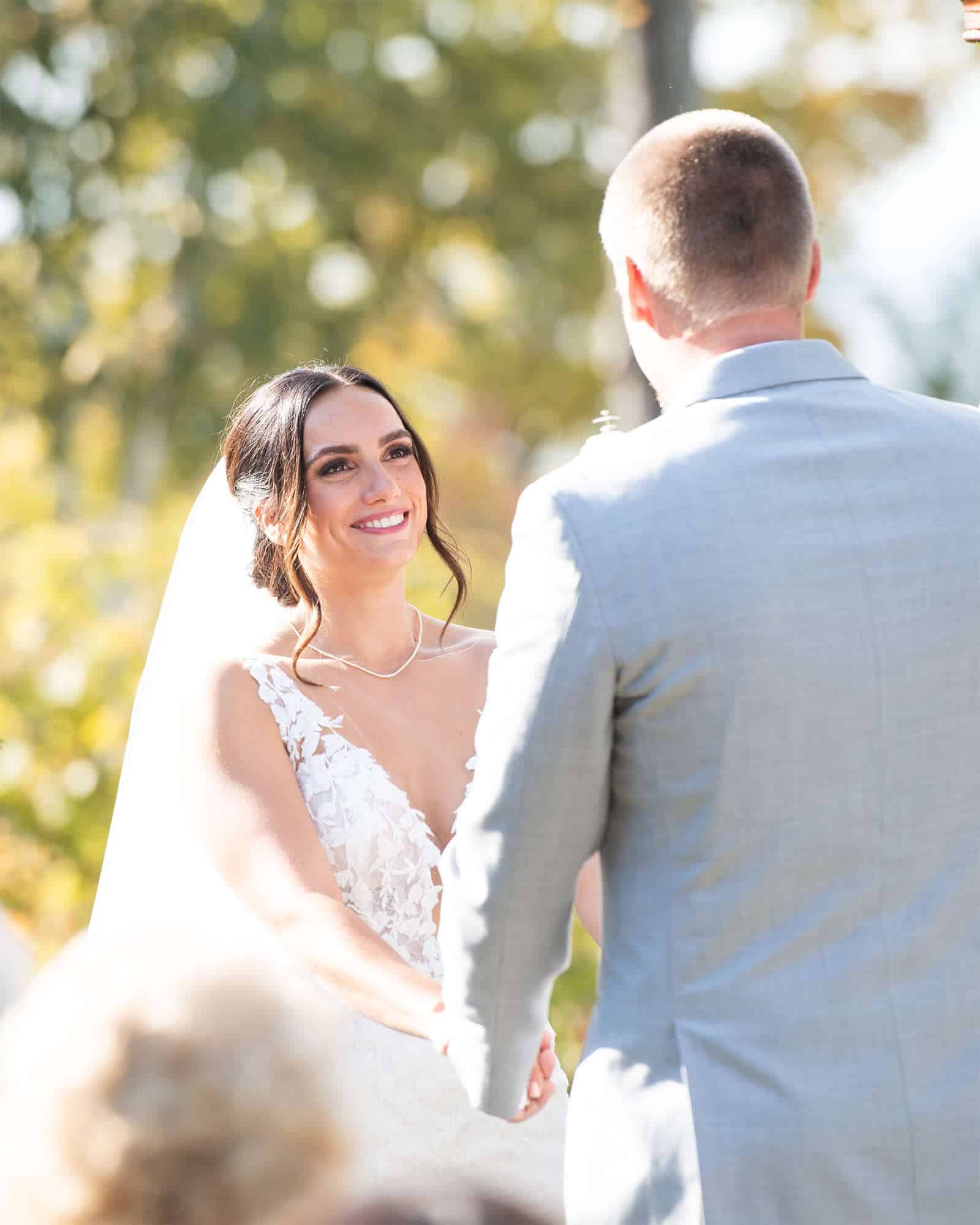 Bride smiles at groom during their Land Resort wedding ceremony