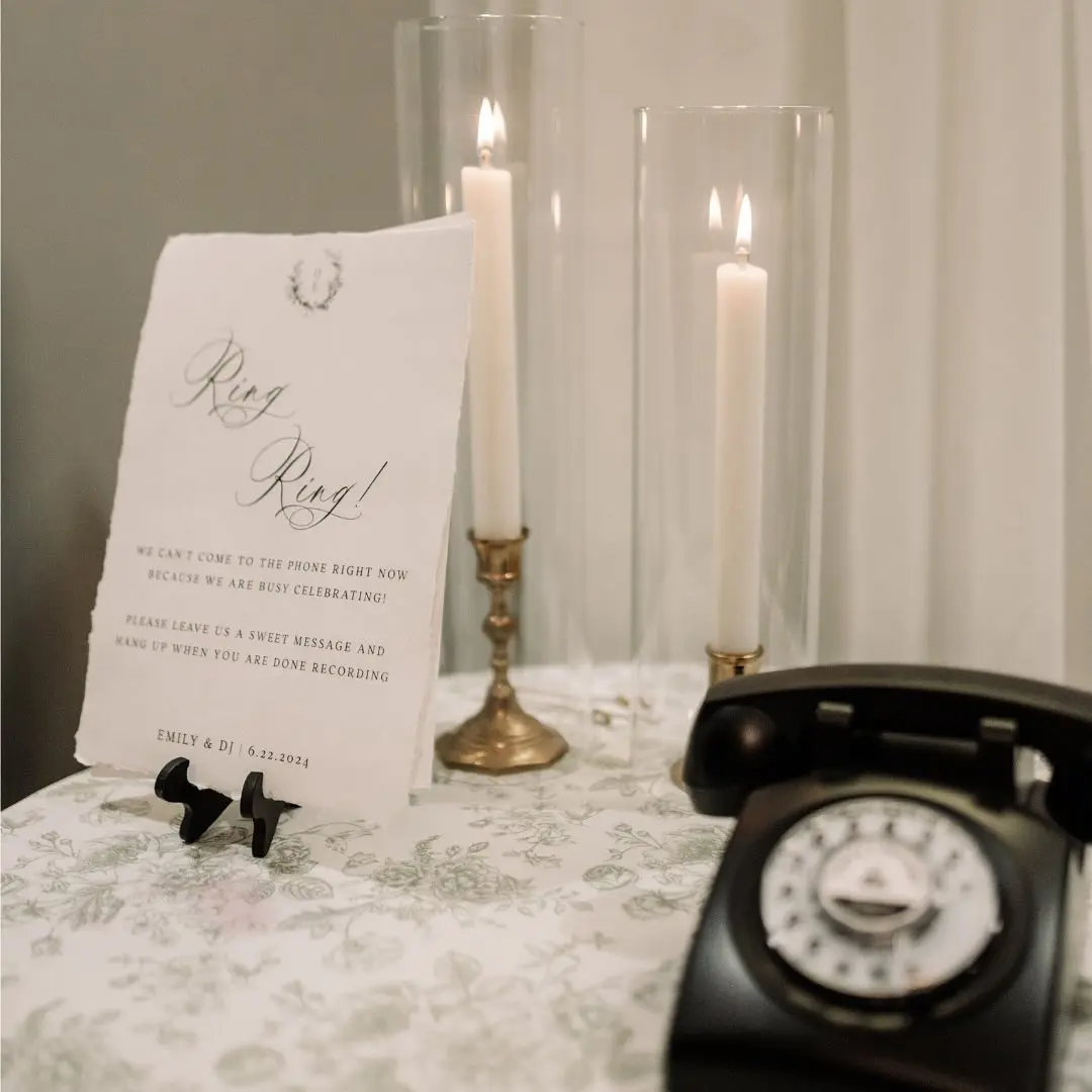 Ring! Ring! signage and black rotary phone on table with floral tablecloth by I Do Decorating & Rental Service