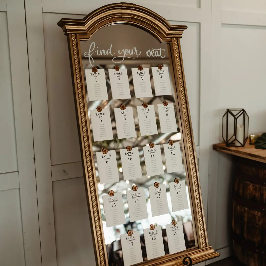 Find your seat charting on gold framed mirror with gold embossed stamping by I Do Decorating & Rental Service