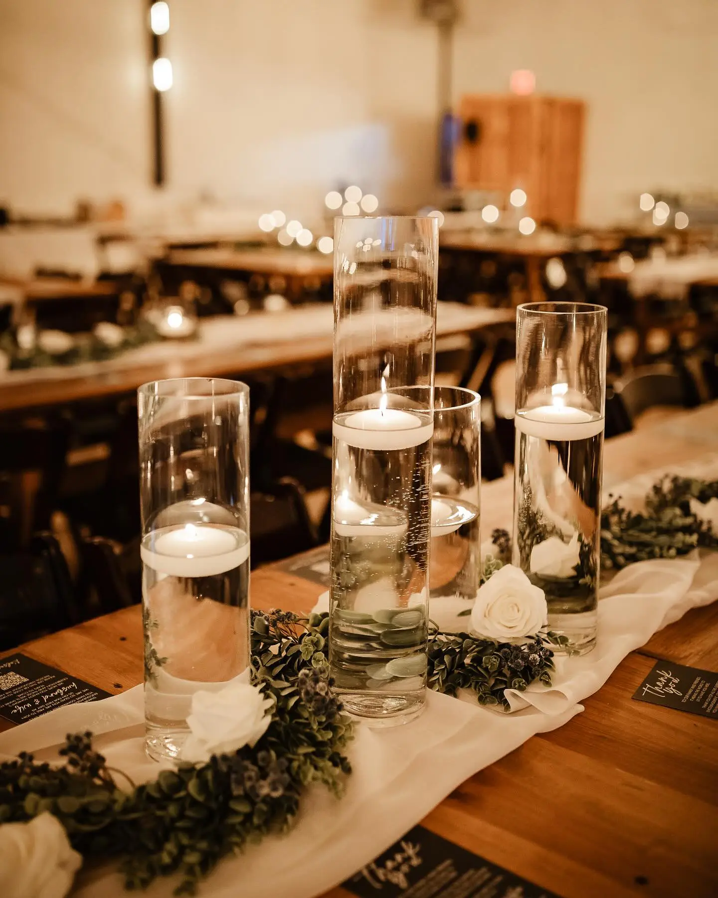 clear cylinder vases with white floating candles and florals by I Do Decorating & Rental Service