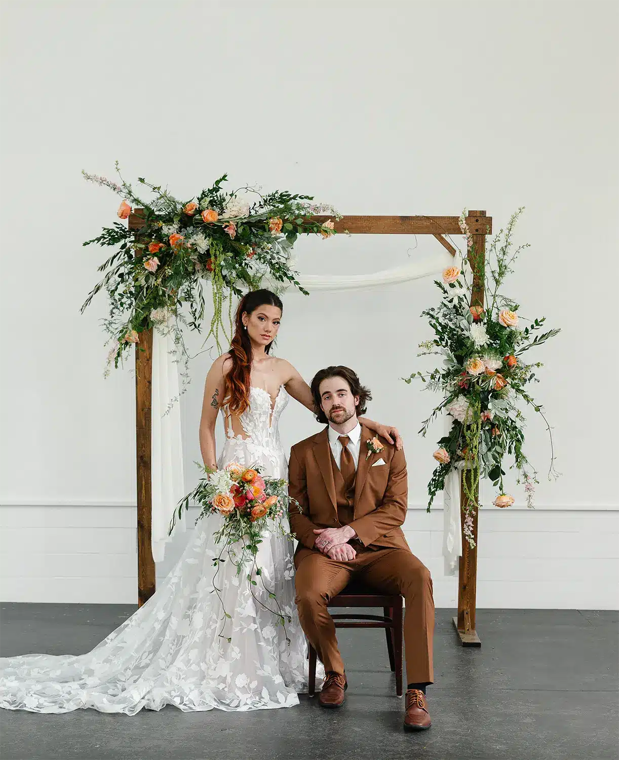 Couple pose at Heritage Hill’s Moravian Chapel under floral drenched arch created by uBloom Oshkosh. Couple pose at Heritage Hill's Moravian Chapel under floral drenched arch created by uBloom Oshkosh.