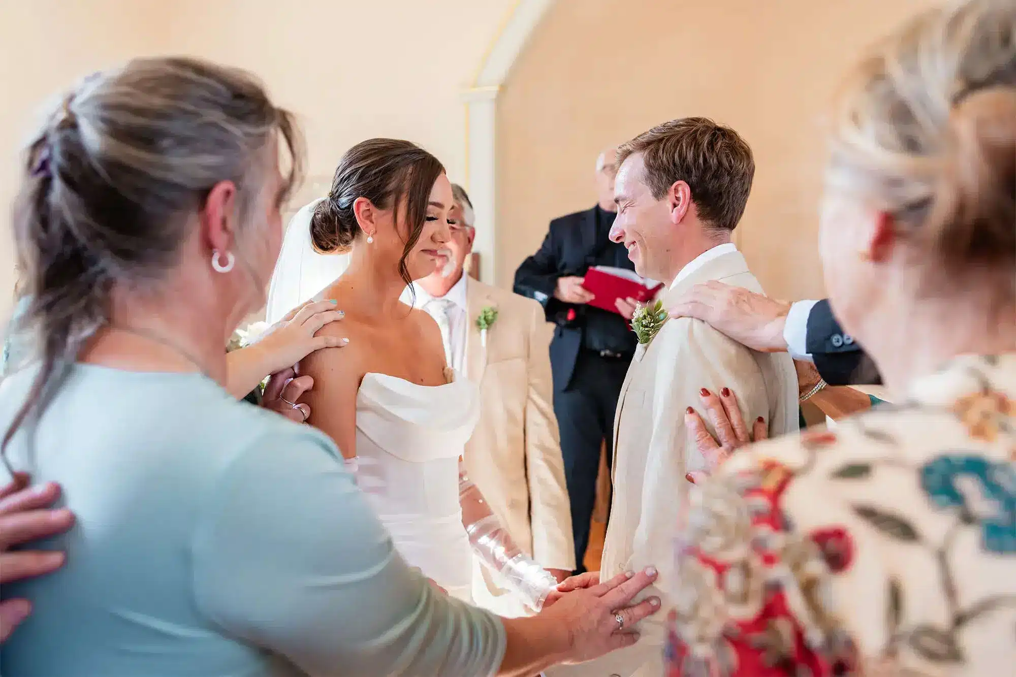 Clintonville-lakeside-wedding-reception-04 Family with hands on bride and groom's shoulders as they share a prayer during ceremony