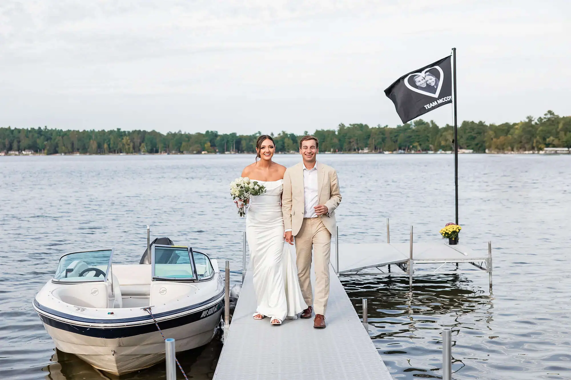 Clintonville-lakeside-wedding-reception-36 Couple walking hand in hand on dock with boat alongside