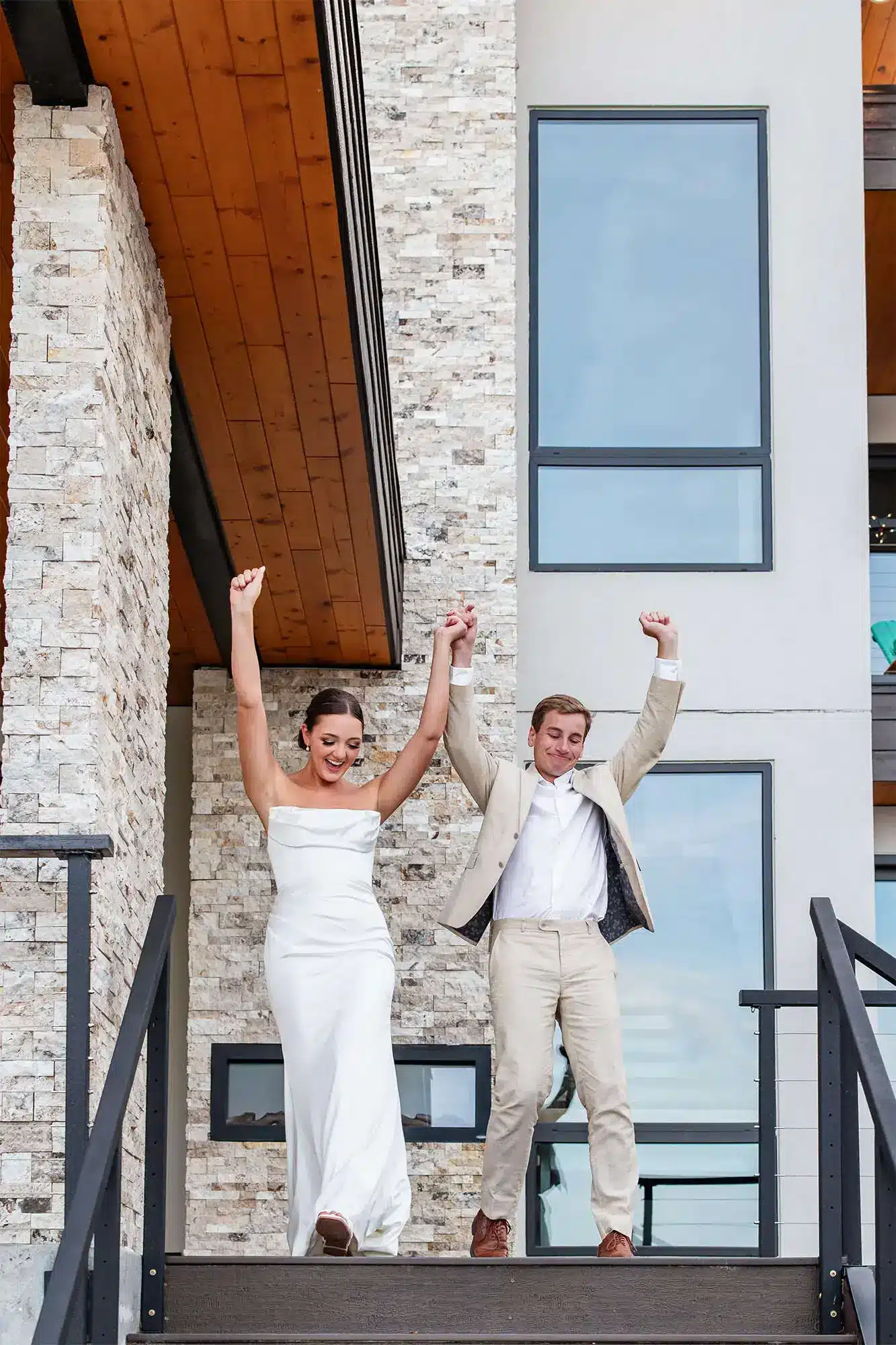 Clintonville-lakeside-wedding-reception-47 Bride and groom with hands in the air as they descend stairs to outdoor reception area