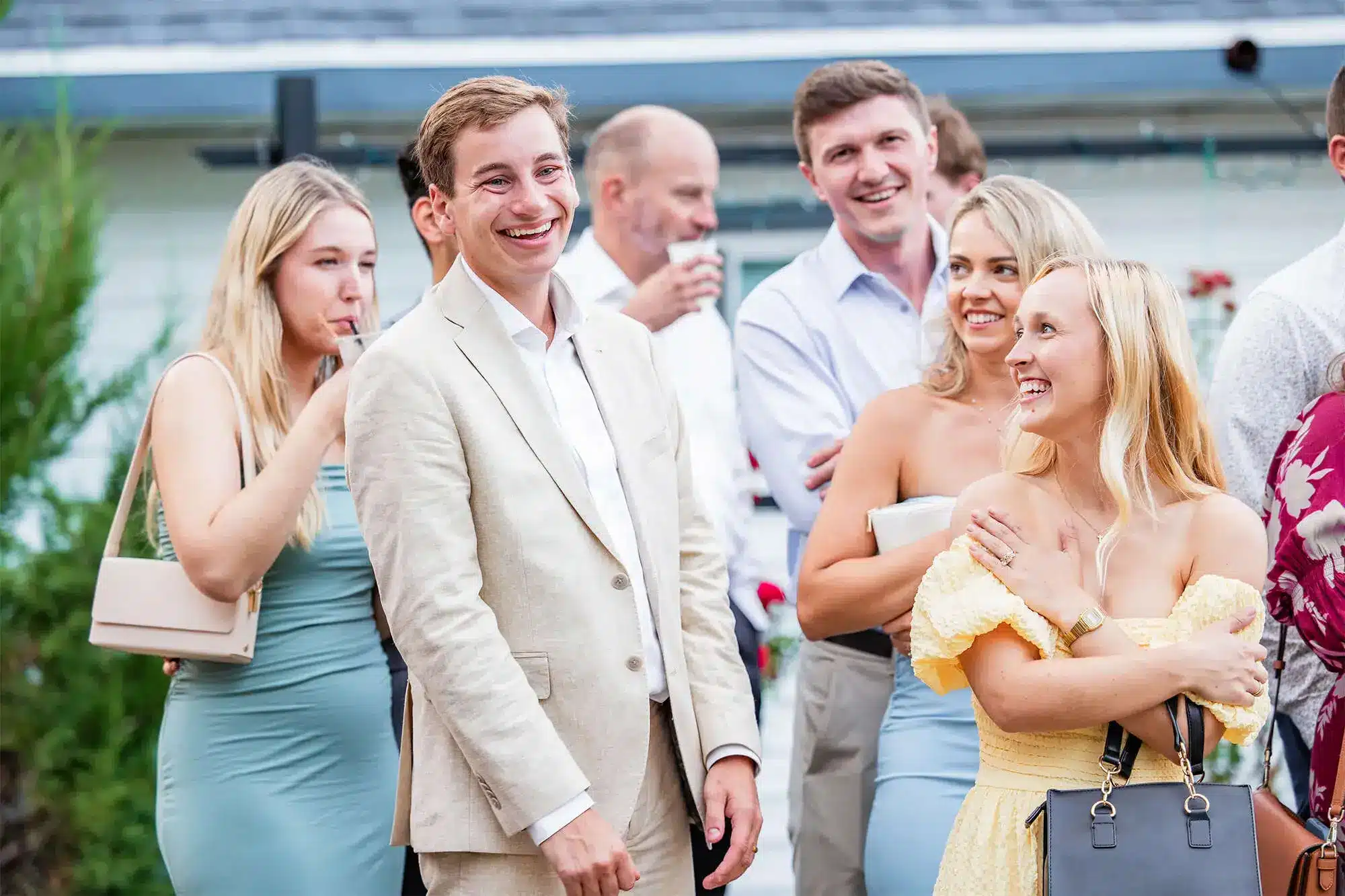 Clintonville-lakeside-wedding-reception-61 Groom laughing and visiting with guests during outdoor cocktail hour.