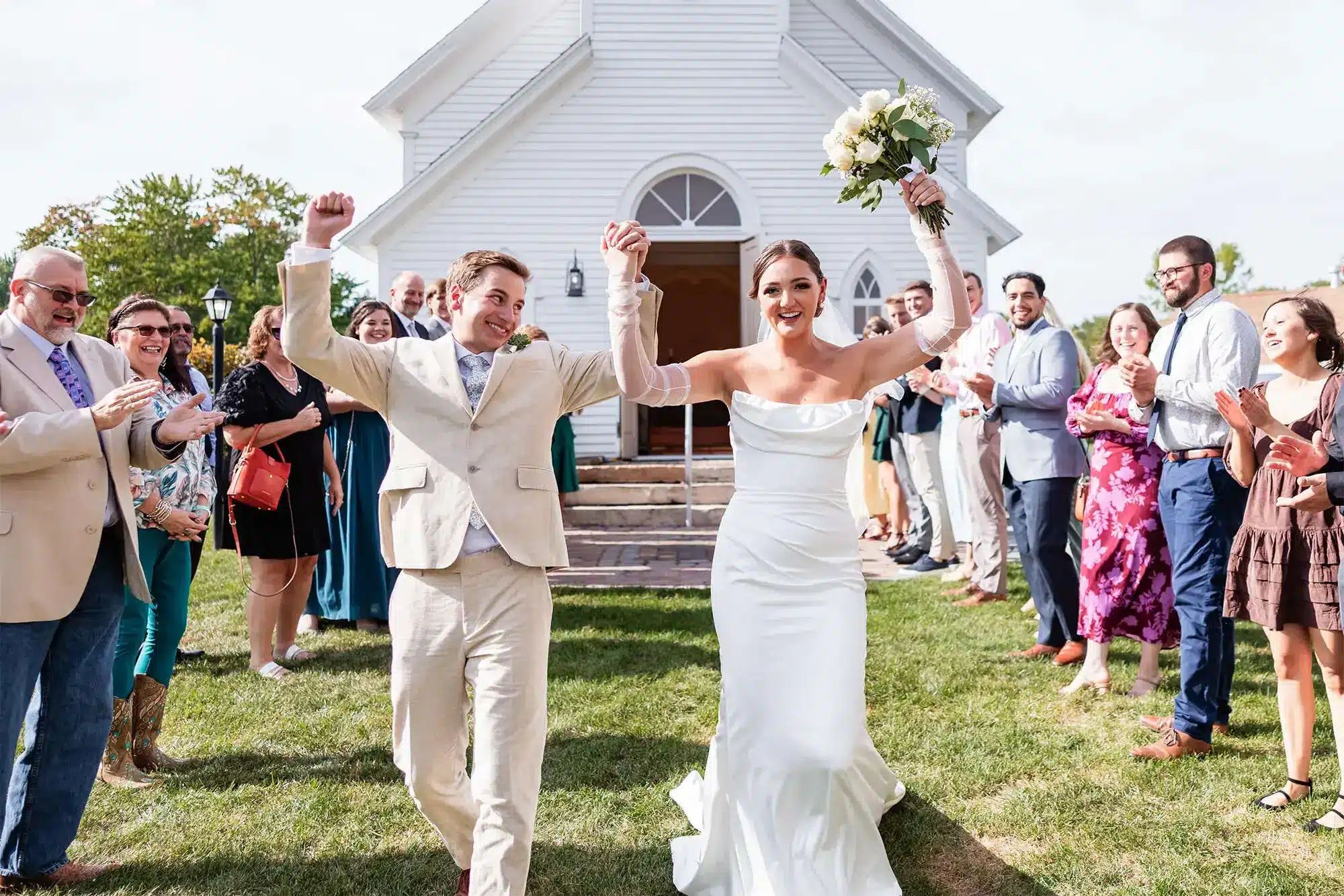Clintonville-lakeside-wedding-reception-7 Couple celebrating nuptials with hands in the air as they exit the chapel