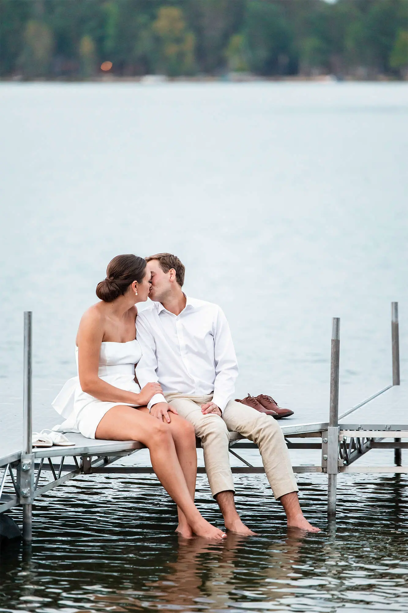 clintonville-lakeside-wedding-reception-79 Bride and groom share a kiss while sitting on dock with their feet in the water