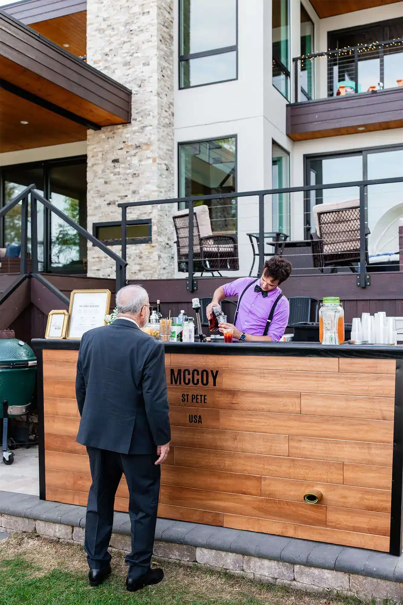 Clintonville-lakeside-wedding-reception-9 Bartender in purple shirt and black suspenders and bowtie serving up a mixed cocktail to guest