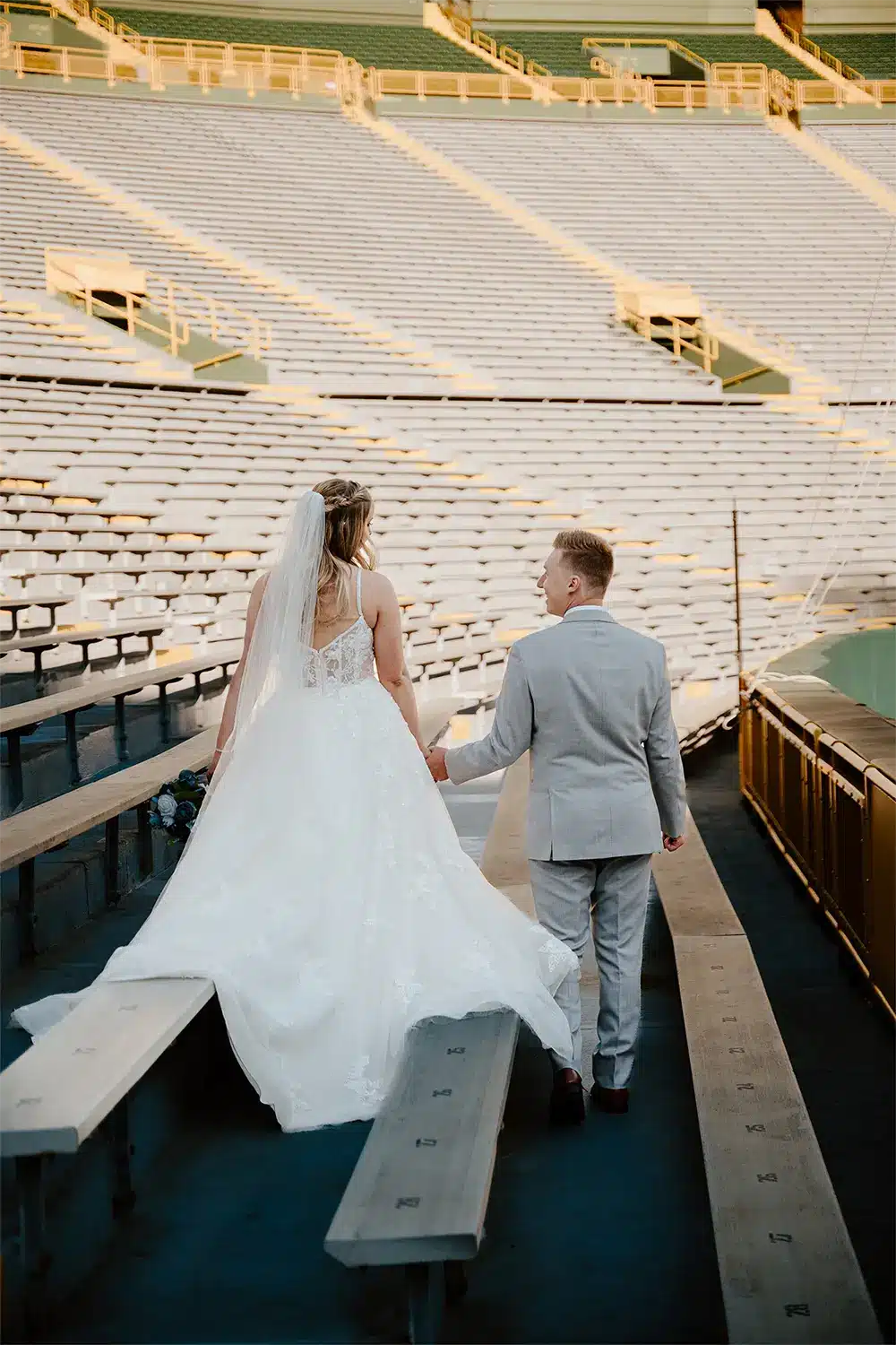 Bride and groom walk hand and hand at Lambeau Field. Bride and groom walk hand and hand at Lambeau Field.