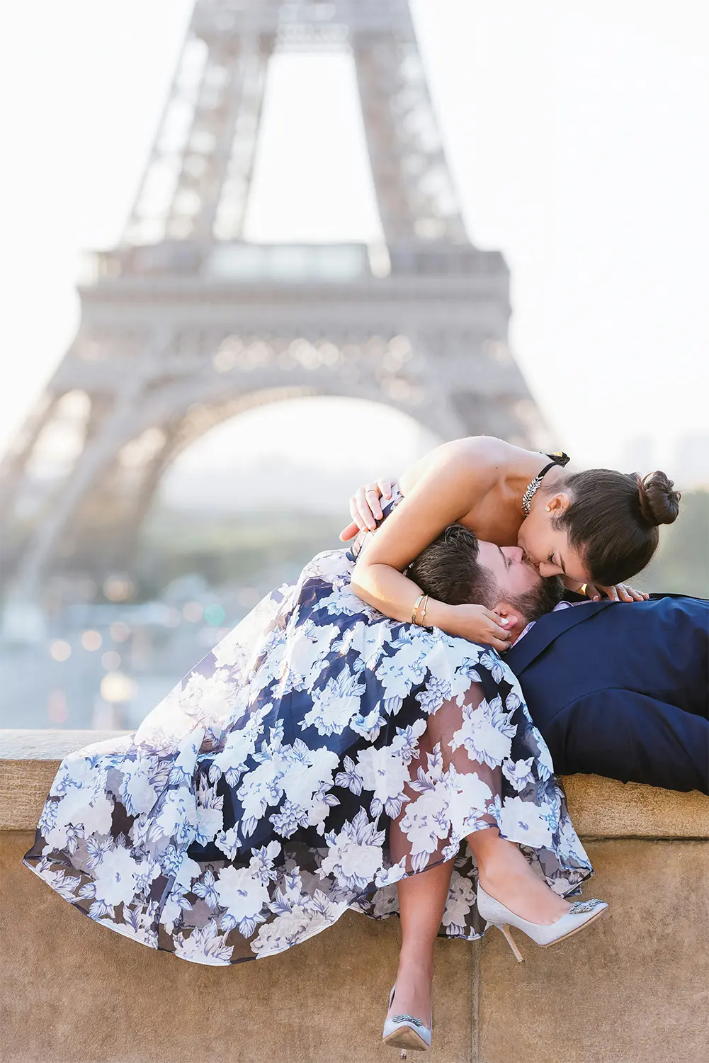 Woman leans over to kisses man with the Eiffel Tower in background. Woman leans over to kisses man with the Eiffel Tower in background.