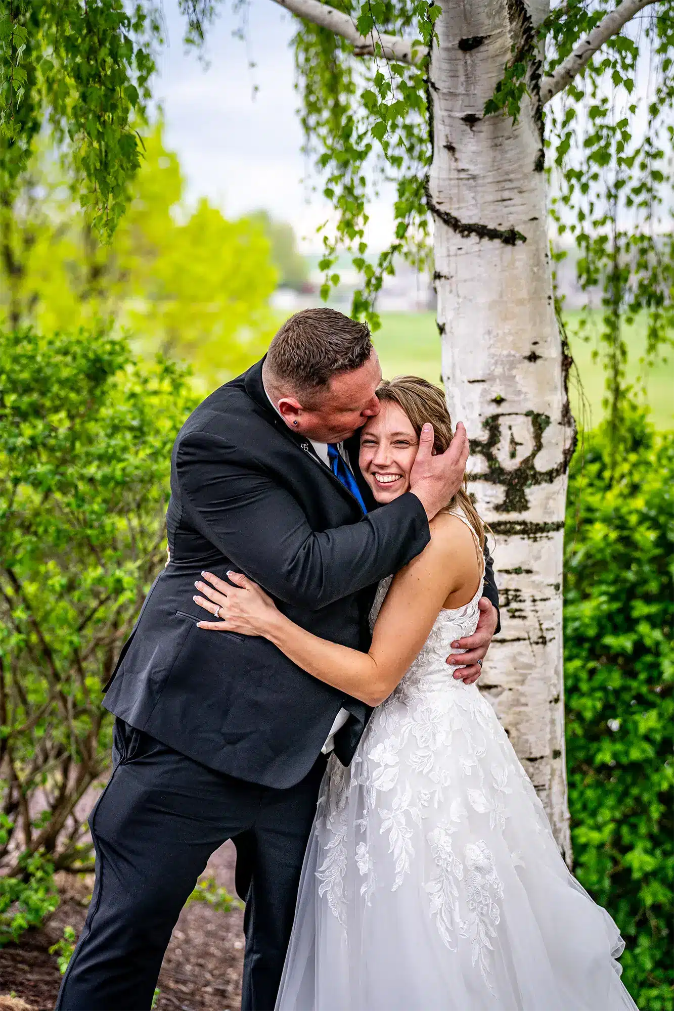 Groom kissing the Bride’s forehead in outdoor scene in Wisconsin. Groom kissing the Bride's forehead in outdoor scene in Wisconsin.