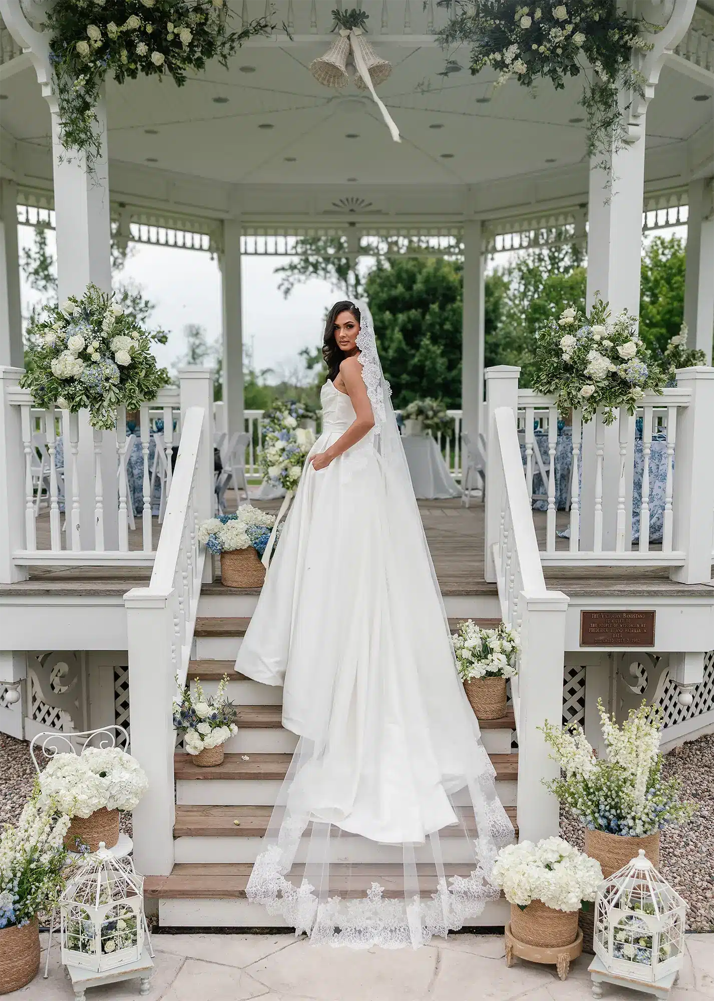 Bride in a white gown and lace trimmed veil stands on the steps of the decorated gazebo at Heritage Hill in Green Bay. Bride in a white gown and lace trimmed veil stands on the steps of the decorated gazebo.
