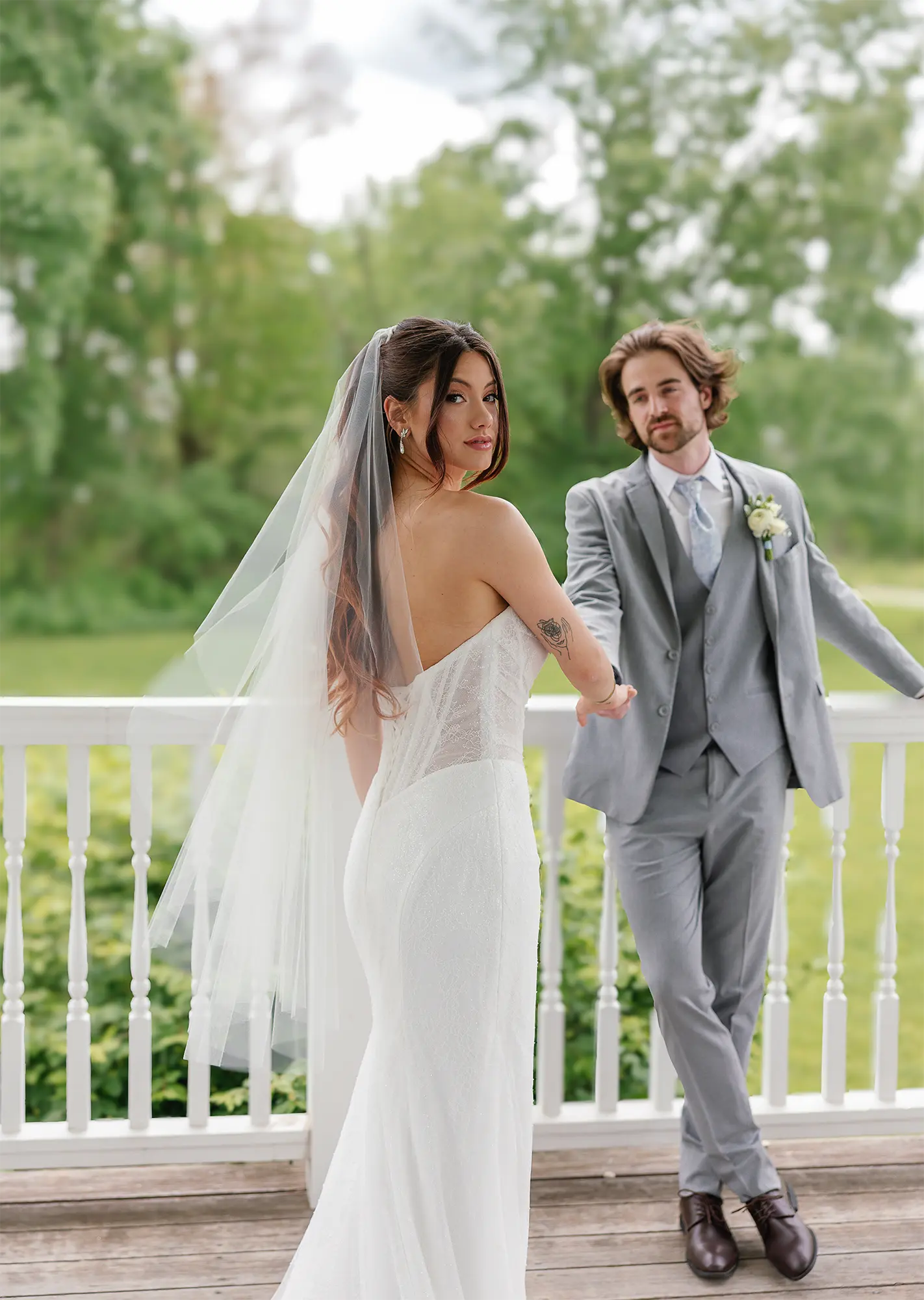 Bride in Maggie Sottero basque waist corset lace mermaid wedding dress in gazebo with groom in light gray suit. Bride in Maggie Sottero basque waist corset lace mermaid wedding dress in gazebo with groom in light gray suit.