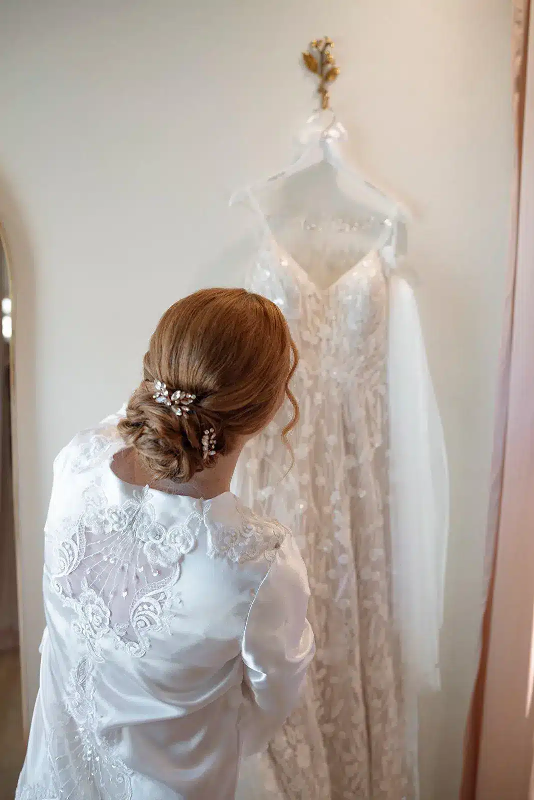 Bride with braided bun looks at gown.