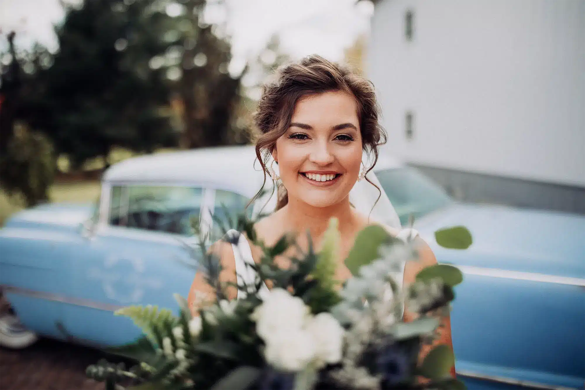 Bride smiles holding bouquet.
