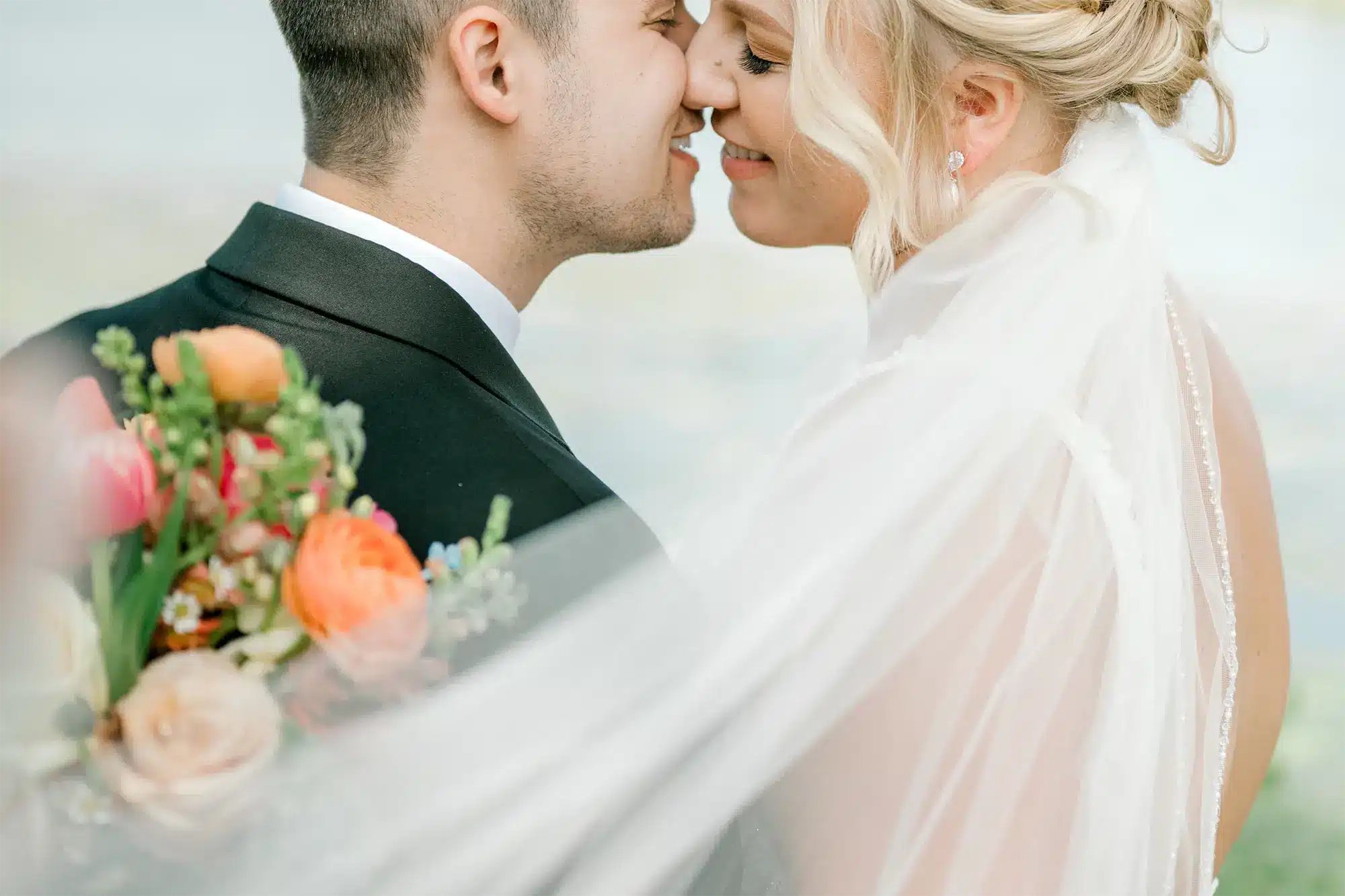 Romantic Bridal Portrait Close-Up Close up of bride and groom sharing kiss with veil and bouquet detail.