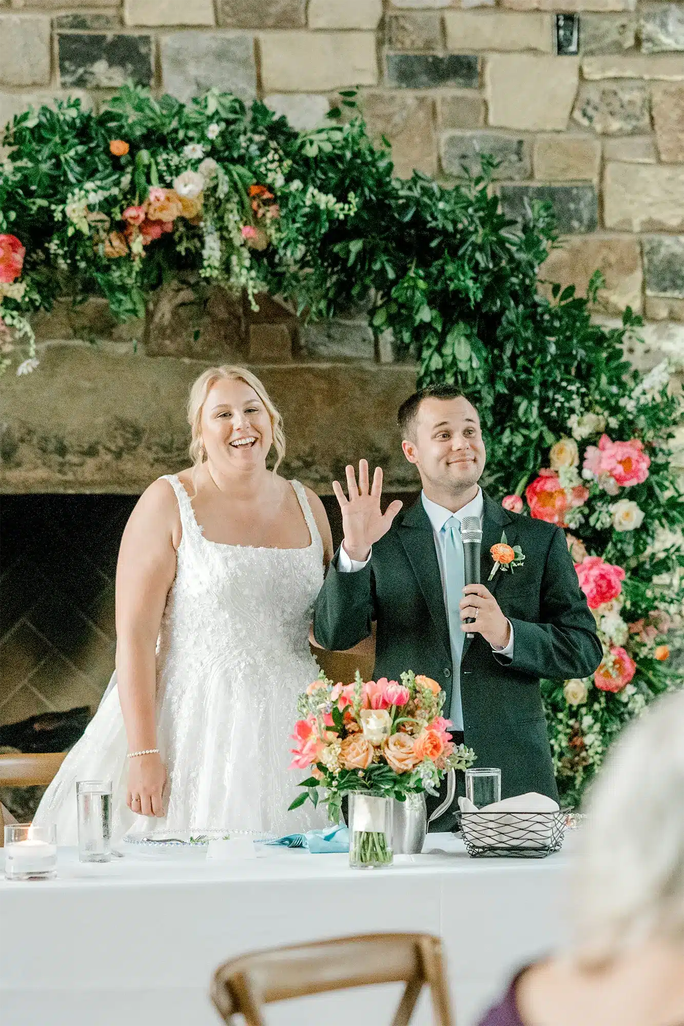 Welcome speech from groom. Bride smiles as groom addresses guests.