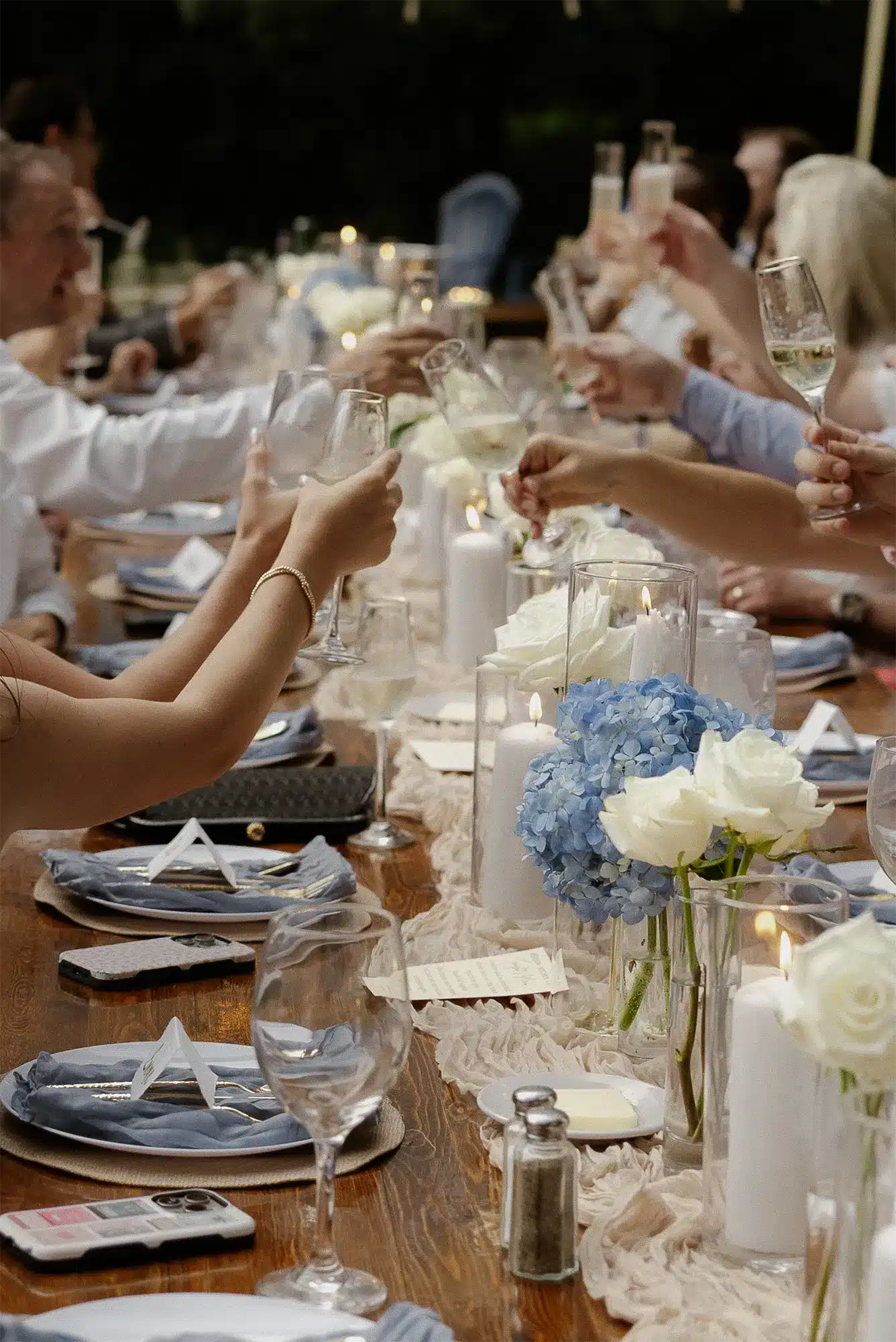 Candlelit Wedding Reception Toast with Blue Hydrangea Centerpieces Wedding reception toast with guests at candlelit table and blue hydrangea centerpieces in Green Lake, Wisconsin.