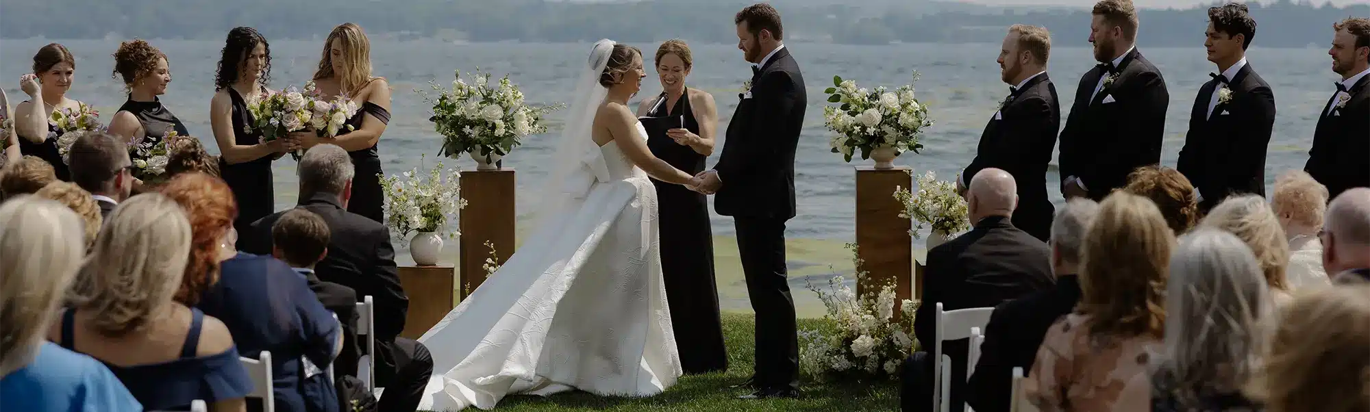 Outdoor waterfront wedding ceremony at the Heidel House on Green Lake, with bride and groom exchanging vows.