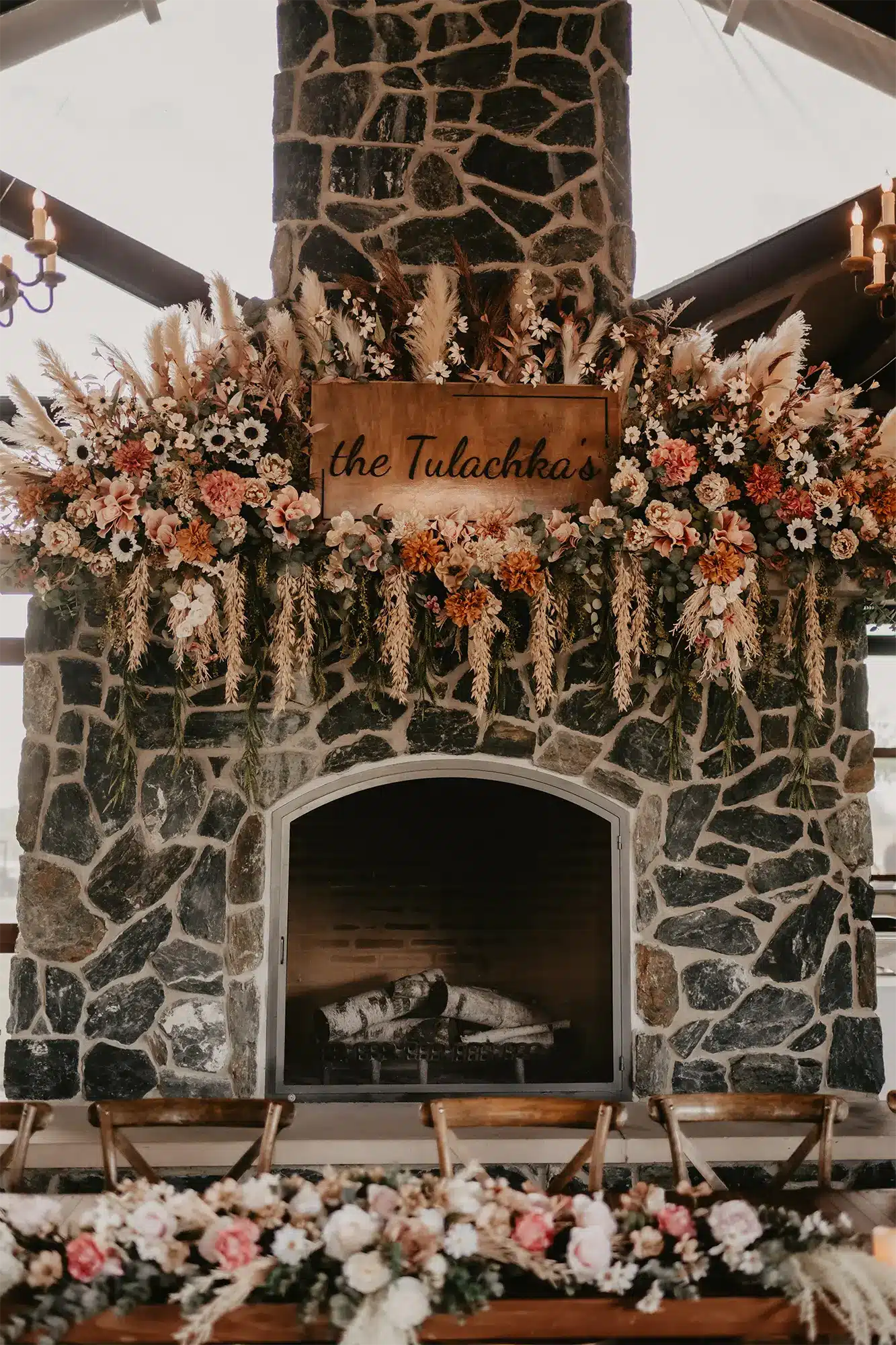 Floral Fireplace Installation at Stone Prairie Reception Stone Prairie reception fireplace with floral installation and custom wedding signage in warm neutral tones